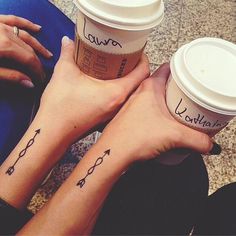 two people with matching tattoos on their arms and legs, holding coffee cups in their hands