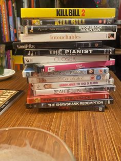 a stack of dvds sitting on top of a wooden table next to a glass bowl