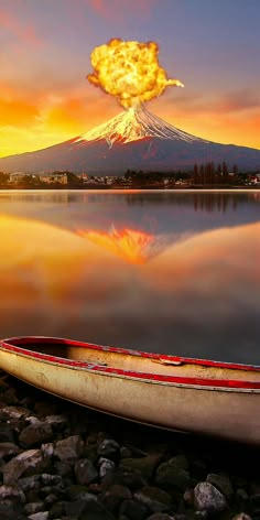 a boat is sitting on the shore with a mountain in the background and clouds above it