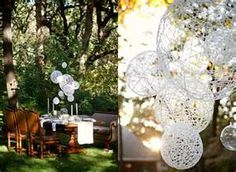 an outdoor dining area with tables and chairs in the grass, surrounded by white paper balls