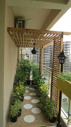 an outdoor walkway with potted plants and lights on the side of it, next to a window