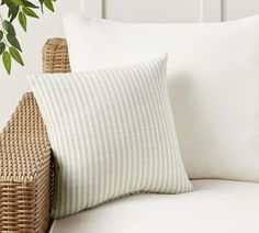 a close up of a pillow on a couch with a plant in the corner behind it