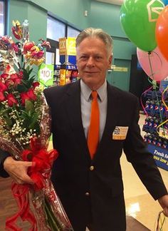 a man in a suit holding flowers and balloons