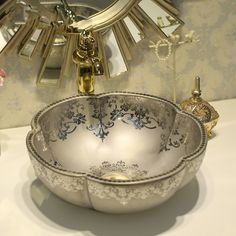 an ornate silver bowl with blue and white designs sits on a table in front of a mirror