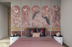 a bed with pink sheets and pillows next to two vases filled with flowers on each side