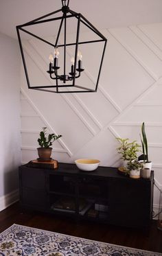 a black chandelier hanging from the ceiling above a table with plants on it