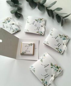 wedding place cards and napkins are laid out on a table with greenery in the background