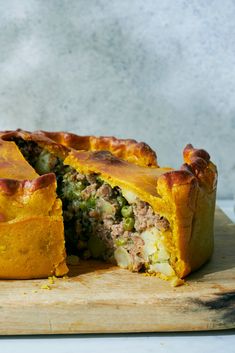 a meat and vegetable pie cut in half on a cutting board