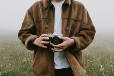 a man standing in a field holding a camera