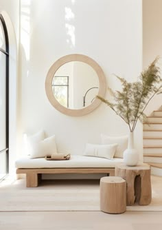 a living room with white furniture and a round mirror on the wall