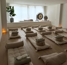 a large room filled with lots of pillows on top of wooden floor next to a window