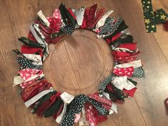 a christmas wreath made out of old fabric pieces on a wooden floor with other items around it