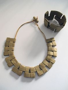 a necklace and bracelet made out of metal strips on a white surface with a wire attached to it