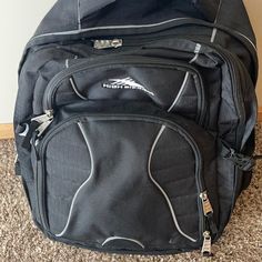 a black backpack sitting on top of a carpeted floor