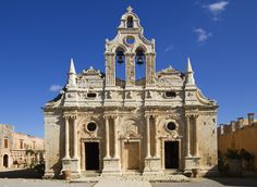 an old church with two bell towers on the front and one at the back, surrounded by stone buildings