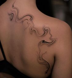 the back of a woman's shoulder with an abstract tattoo design on her left side