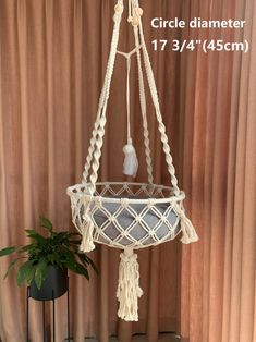 a white macrame hanging from a ceiling with a potted plant in it