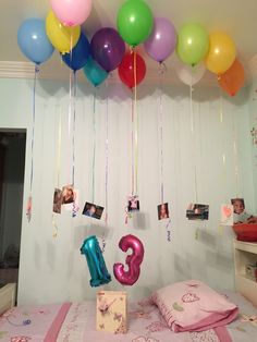 balloons are hanging from the ceiling above a bed