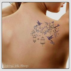 the back of a woman's shoulder with blue flowers and birds flying around it