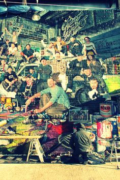 a man sitting in front of a wall with lots of skateboard pictures on it