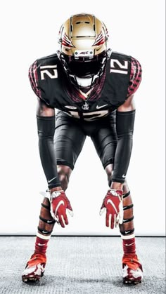 a football player in black and red uniform with his hands on his knees, standing against a white background