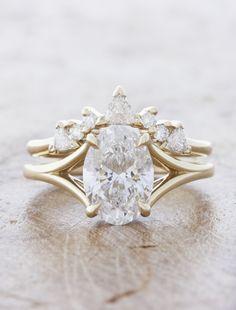 a pear shaped diamond ring on top of a piece of wood with three smaller pears