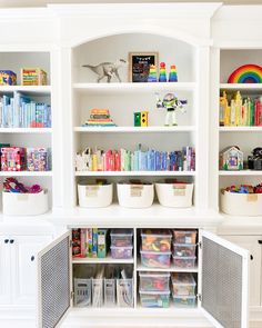 a white bookcase filled with lots of books next to other shelves and bins