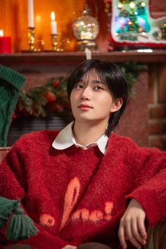 a person sitting in a chair with a red sweater and candles on the wall behind them