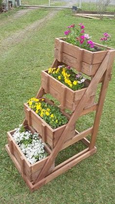 three wooden planters are stacked on top of each other with flowers in the bottom