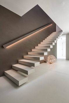 a white staircase leading up to the top floor in a modern house, with lights on either side