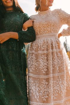 two women standing next to each other wearing dresses and holding hands on their hipss