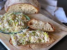 a wooden cutting board topped with slices of bread covered in coleslaw and sprouts