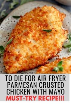 two pieces of fried parmesan crusted chicken on a white plate with herbs