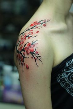 a woman's shoulder with red flowers and leaves painted on the back of her arm