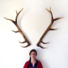 a woman standing in front of two deer antlers