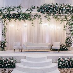 a white couch sitting on top of a set of stairs next to a wall covered in flowers