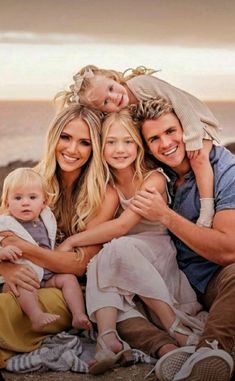 a man, woman and child are sitting on the beach with their arms around each other