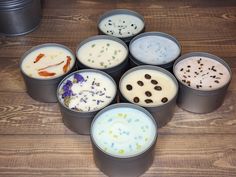 six tins filled with different types of food on top of a wooden table next to a canister