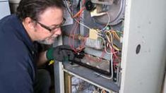 a man working on an air conditioner in his home with wires attached to it