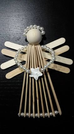 an angel made out of wooden sticks with pearls and beads on it's sides