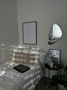 a bed with white sheets and pillows next to a mirror on the wall above it