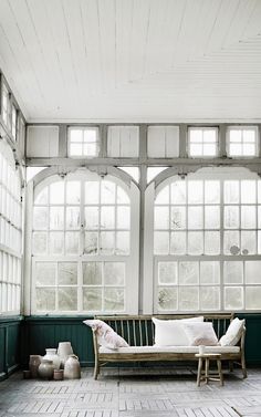 a wooden bench sitting in the middle of a room with lots of windows on it