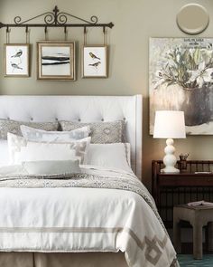 a white bed sitting under two pictures on the wall