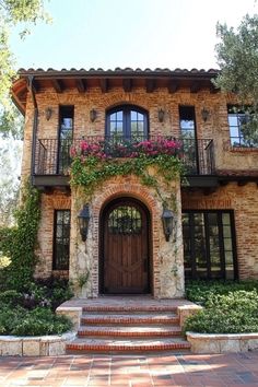 a large house with lots of windows and flowers on the front door, steps leading up to it