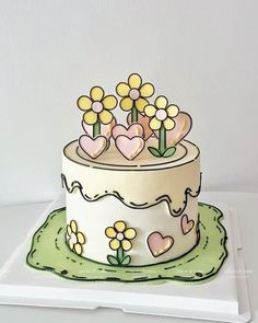 A real cake that looks like a drawing. Green at the bottom to mimic grass and a white icing base with yellow flowers and pink hearts on top and the side. Also yellow icing on the top of the cake and going down the edges slightly. Kue Fondant, Comic Cake, Cartoon Birthday Cake, Cake Drawing, Cartoon Cake