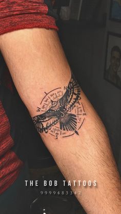 a man's arm with a tattoo on it that has a bird and compass