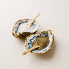 two oyster shells with spoons in them on a white surface