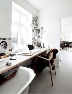 a desk with two laptops on it in front of a window and a chair