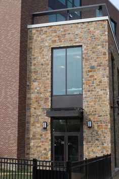 a tall brick building with a black fence around it's front entrance and windows