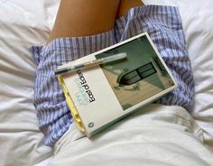 an open book sitting on top of a bed next to a person's legs